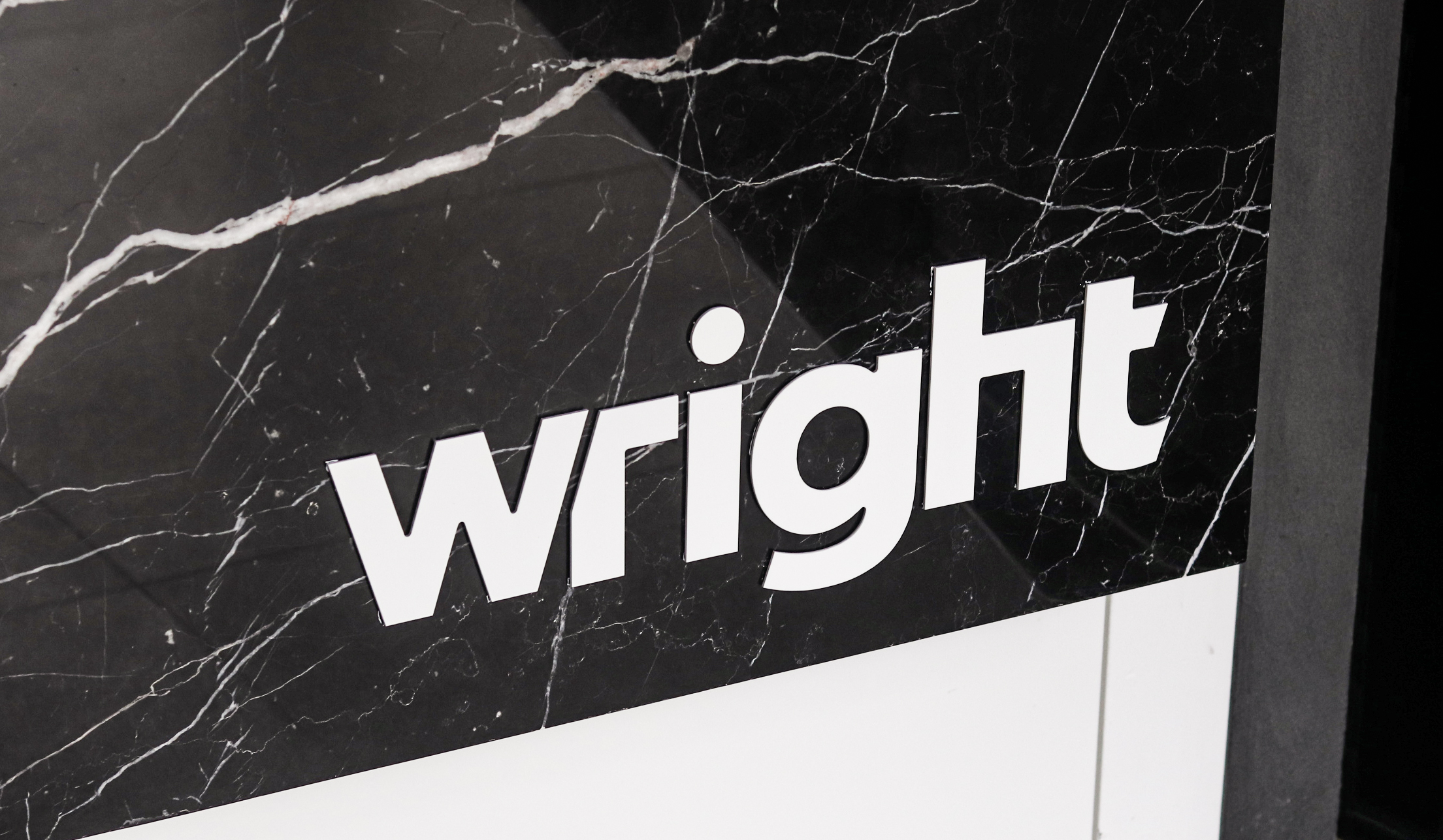 Close-up of the Wright wordmark on black marble signage, showing the angled cut